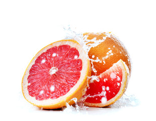 Splashing of liquid onto fresh grapefruit against white background