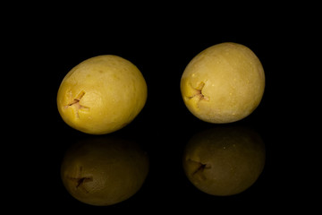 Group of two whole marinated green olive isolated on black glass