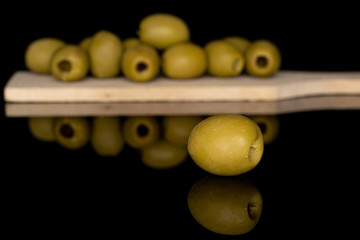 Group of eleven whole marinated green olive on wooden cutting board isolated on black glass