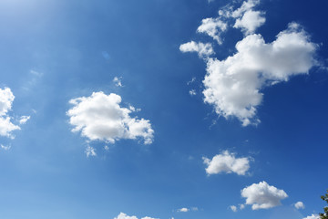 Blue sky background with green fields and white clouds.
