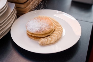 three pancakes with banana in white dish