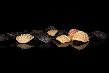 Lot of whole colorful pasta orecchiette in row isolated on black glass