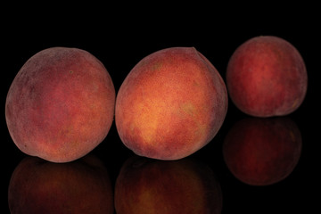 Group of three whole sweet red peach isolated on black glass