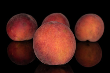 Group of four whole sweet red peach isolated on black glass
