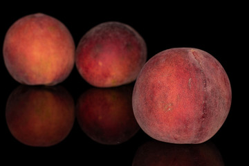 Group of three whole sweet red peach front focus isolated on black glass