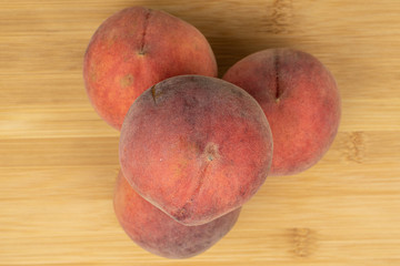 Group of four whole sweet red peach flatlay on light wood