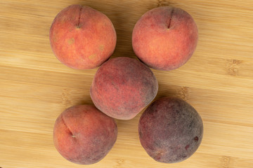 Group of five whole sweet red peach flatlay on light wood