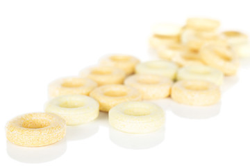 Lot of whole disordered round pale yellow candy isolated on white background