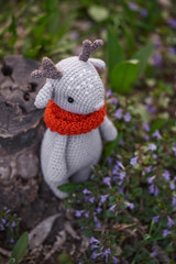 Beautiful handmade soft toy fawn. Outdoor photography, grass and a small stump.