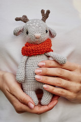 Beautiful handmade soft toy fawn. Outdoor photography, grass and a small stump.