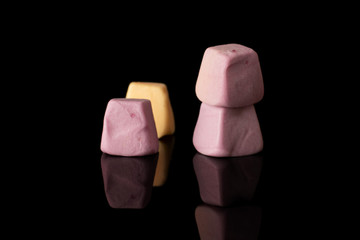 Group of four whole soft pastel candy isolated on black glass