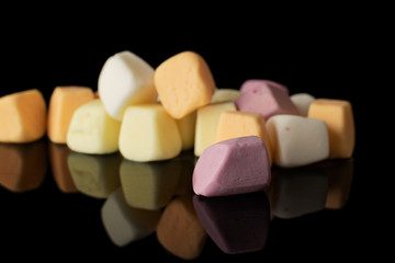 Lot of whole disordered soft pastel candy isolated on black glass