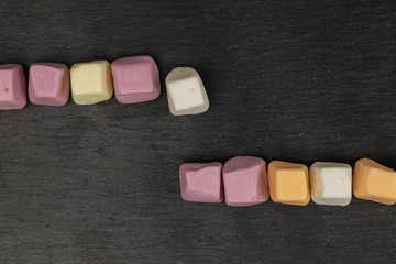 Group of ten whole soft pastel candy flatlay on grey stone