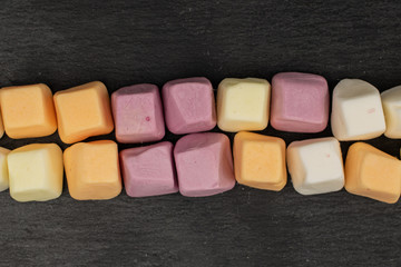 Lot of whole soft pastel candy in row flatlay on grey stone