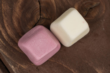 Group of two whole soft pastel candy flatlay on brown wood