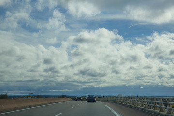 Fototapeta na wymiar Asphalt road through the green field and clouds on blue sky in autumn day