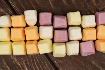 Lot of whole soft pastel candy flatlay on brown wood