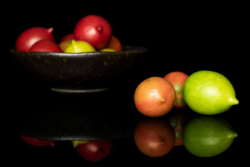 Fototapeta na wymiar Group of ten whole fresh tomato de barao on glazed bowl isolated on black glass