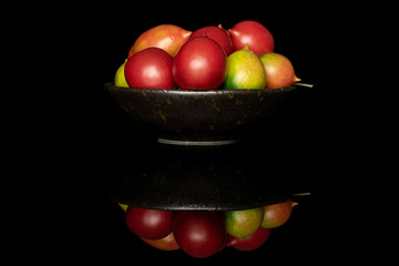 Lot of whole fresh tomato de barao on glazed bowl isolated on black glass