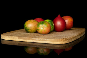 Fototapeta na wymiar Group of six whole fresh tomato de barao on bamboo cutting board isolated on black glass
