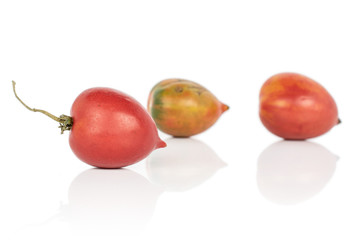 Group of three whole fresh tomato de barao one with stem isolated on white background
