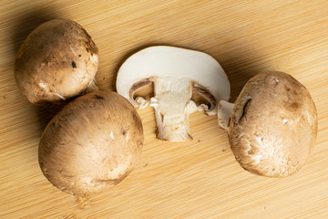 Group of three whole one slice of fresh brown mushroom champignon flatlay on light wood