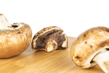 Group of three whole fresh brown mushroom champignon on bamboo cutting board isolated on white background
