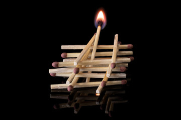 Lot of whole brown safety match one burning isolated on black glass