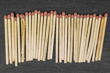 Lot of whole brown safety match in row flatlay on grey stone