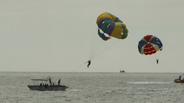 Paraglider landing on the Boat Over The Sea