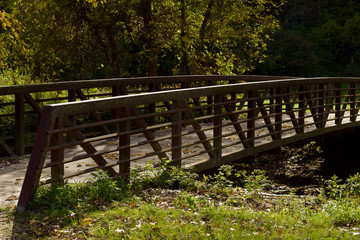Fototapeta na wymiar Landscape view of a rustic bridge over a river in a woodland natural public park area