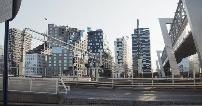 Cinema 4K gimbal wide shot with parallax motion of the Oslo central train station with train passing and buildings in the Barcode section of the new and popular Opera quarter project, in Oslo Norway.