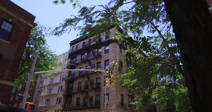Dolly shot of brick apartment building at an intersection in Brooklyn Heights, New York in a sunny summer weekday.