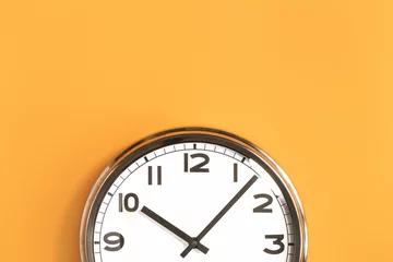 Foto op Canvas Part of analogue plain wall clock on trendy pastel orange background. Ten o'clock. Close up with copy space, time management or school concept and summer or winter time change © taniasv