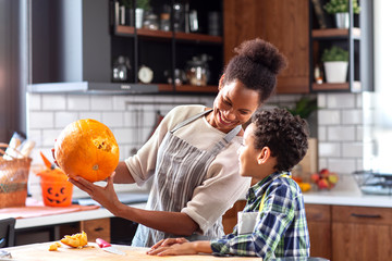 Mother with his son prepare pumpkin for halloween in the kitchen