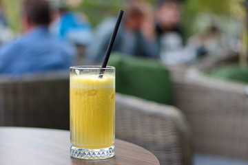Glass of orange juice with straw on the table in restaurant