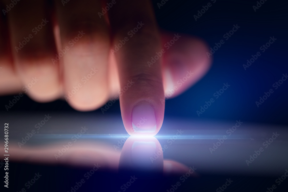 Poster finger touching tablet with dark background with copyspace