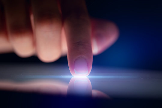 Finger touching tablet with dark background with copyspace