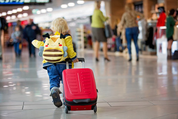 Cute  baby boy, running late for boarding to flight in airport transit hall near departure gate. Active family lifestyle travel by air with child