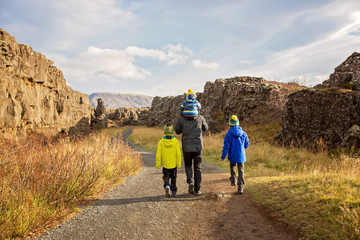 Obraz premium Father with three children, enjoying a sunny day in Thingvellir National Park rift valley, Iceland