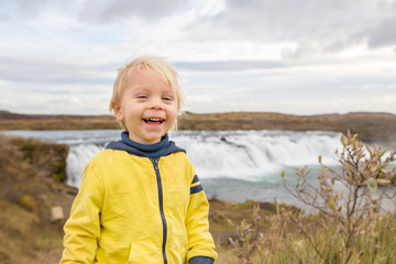 Portrait of a smiling baby boy near smaller waterfall around Gullfoss, Iceland
