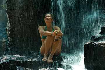 Fototapeta na wymiar attractive and happy mid adult woman with grey hair 40s or 50s enjoying blissful and free at beautiful tropical waterfall feeling the purity and beauty of nature