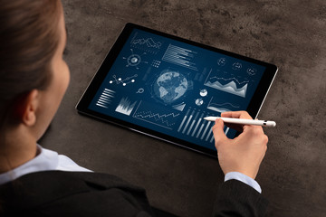 Business woman verifying reports on tablet with pencil in business suit