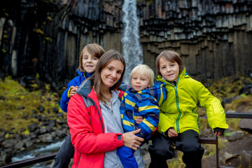 Happy children, posing in front of beautiful waterfall in Skaftafell national park in Iceland
