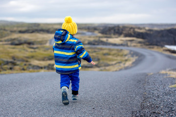 Fototapeta premium Children, walking on a curved road near ocean in beautiful nature in Snaefellsjokull National Park in Iceland, autumntime