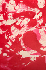 This a photograph of a Red and White abstract marbleized design created using nail polish