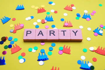 Party word with colorful confetti, on yellow background. Holiday concept.