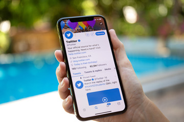 Twitter business Woman hand holding iPhone X with social networking service Twitter