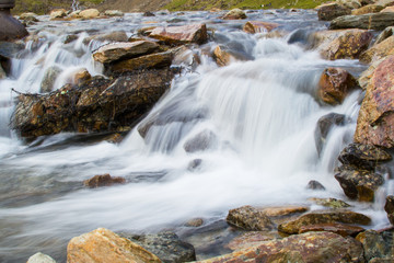 Fototapeta na wymiar Long exposure picture of small waterfalls between boulders making a brook in Snowdonia, Wales
