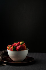 fresh strawberries in bowl on dark background